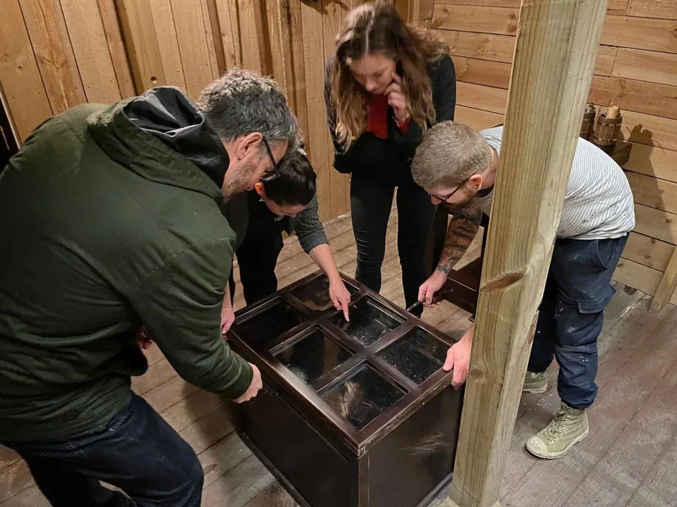 A work team gathered around a locked chest inside an Escape This escape room